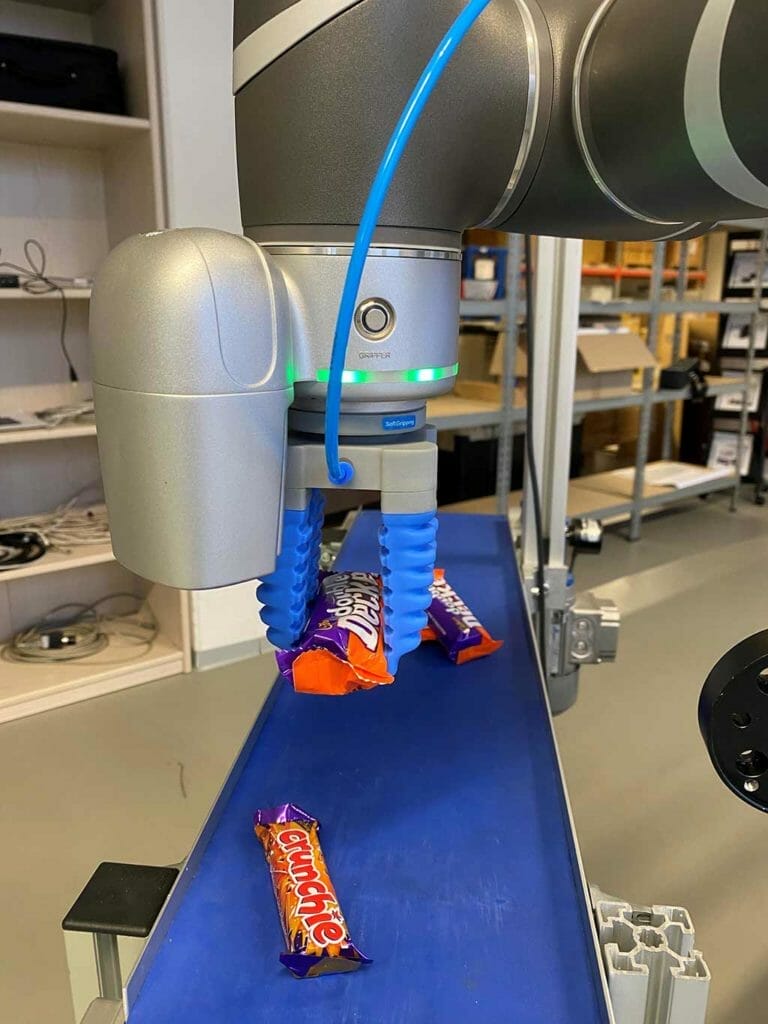 TM robot recogiendo dulces de la línea de montaje